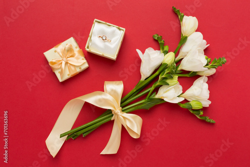 White freesia flower and gift box with diamond ring on color background  top view
