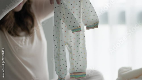 Pregnant woman preparing and planning baby clothes ready for the maternity hospital photo