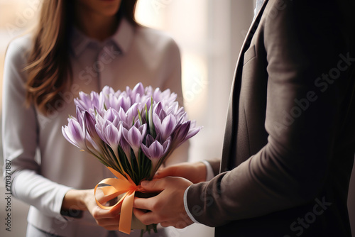 A man gives a woman crocuses in a vase