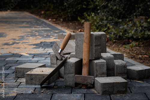 Hammer and trowel on the sidewalk with concrete bricks.