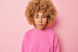 People positive emotions concept. Studio waist up of young happy pretty fit European female standing in centre isolated on pink background wearing sweater keeping hands down calm and relaxed
