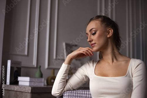Pensive young perfect lady sit on chair in living room at home, thought looking away. Fatigue lovely woman with emotional stress posing inside. Mental health and depression concept. Copy ad text space