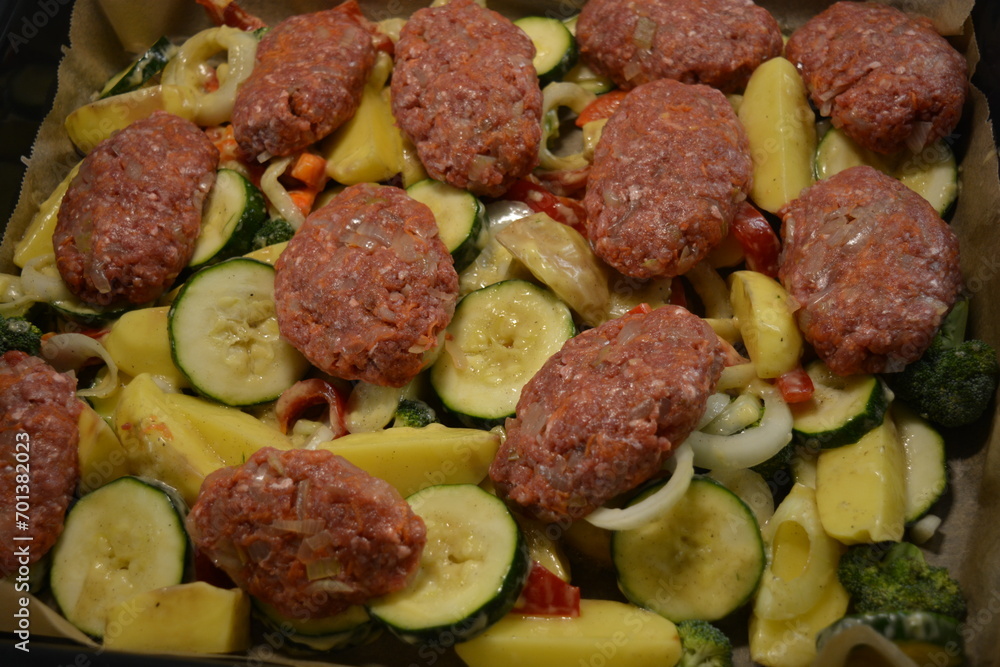 Healthy, wholesome, high-quality food, fresh chopped vegetables and cutlets placed on a large metal baking sheet. Healthy, wholesome, high-quality food, fresh chopped vegetables and cutlets placed on a large metal baking sheet.