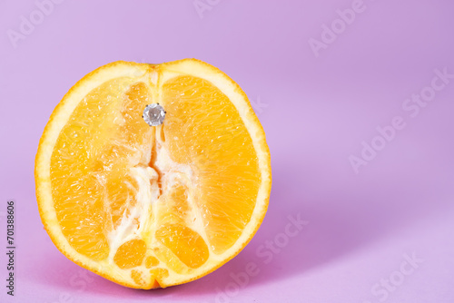 Intimate piercing. Minimal piercing concept. Orange with inserted iron decoration, piercing
