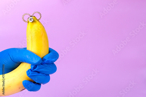 Intimate piercing. Minimal piercing concept. Banana with inserted iron decoration, piercing