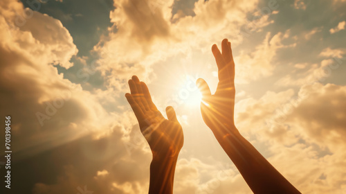 Two hands reaching upwards towards the sunlight photo