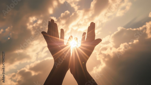 Two hands reaching upwards towards the sunlight photo