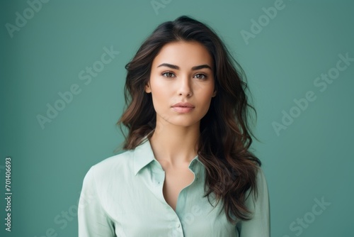 Portrait of beautiful young brunette woman in blue shirt on green background