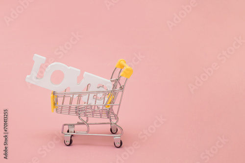 White love sign in a shoping cart on a pastel pink background