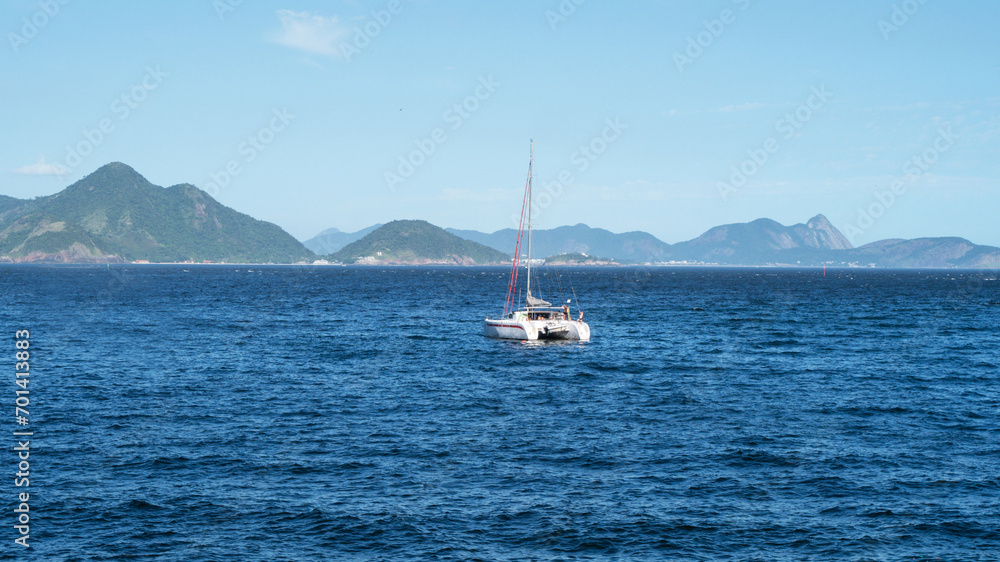 Nautical catamaran in the sea of Rio de Janeiro, with mountains in the background.