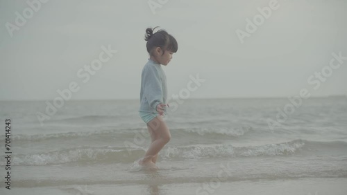 The child happily plays in the waves on the seashore. A girl playing in the waves on the beach. S-log, ungraded