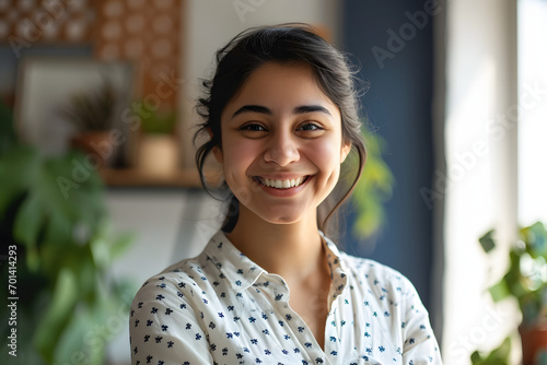 Cheerful indian girl standing at home office looking at camera photo