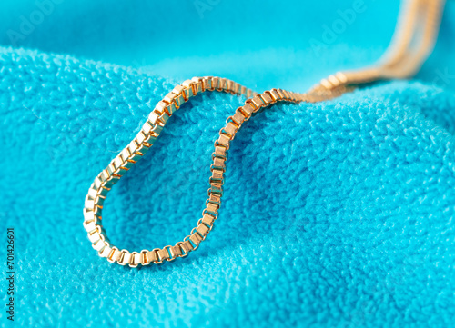 Gold chain on blue fabric. Close-up © schankz
