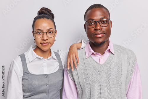 Portrait of woman and man dressed in formal clothes posing side by side look with serious expression at camera being professionals isolated over white background. Two colleagues being at work