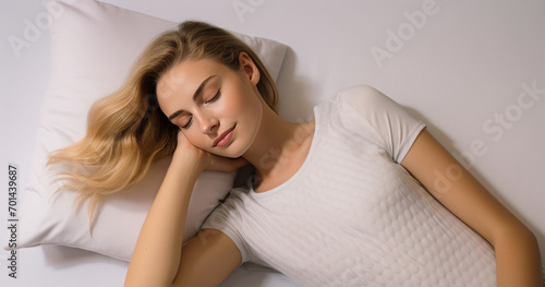 A beautiful young lady with long hair is enjoying a peaceful sleep on a comfortable white bed, wrapped in a soft pillow. The concept conveys an atmosphere of relaxation and tranquility. © mimi