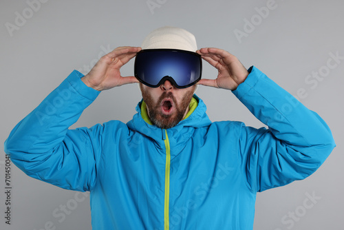 Winter sports. Emotional man in ski suit and goggles on gray background