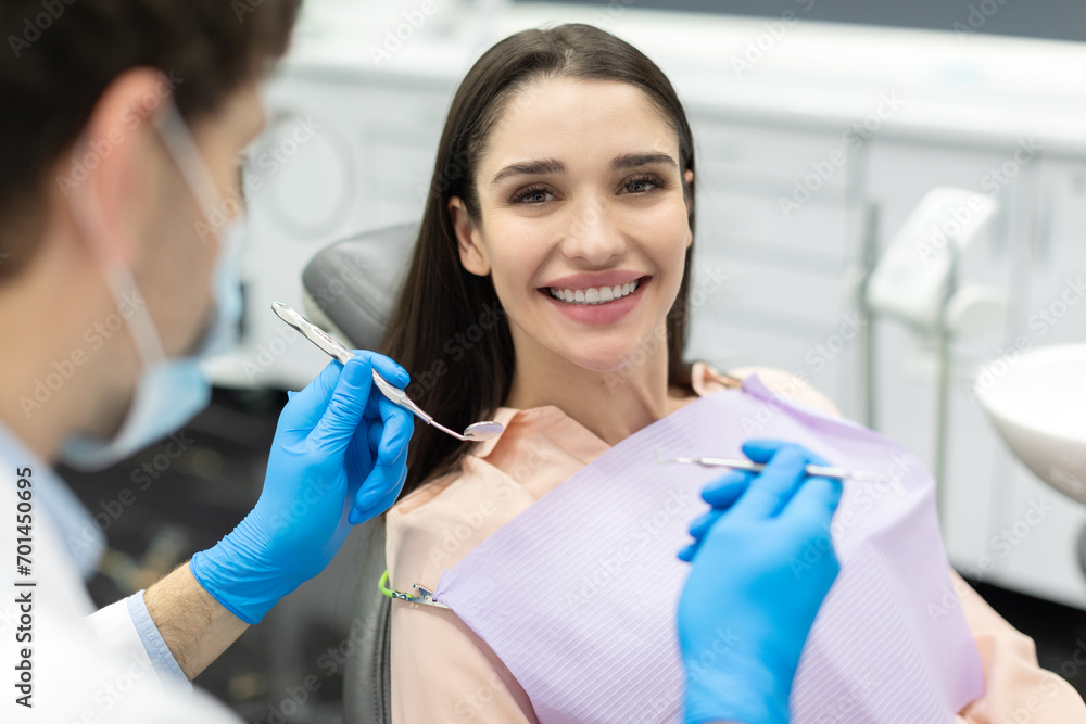 Young caucasian woman with perfect smile sitting in dental office, come to treat spoiled teeth, looking and smiling at camera