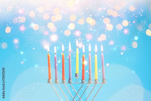 Hanukkah celebration. Menorah with burning candles on light blue background with blurred lights, closeup