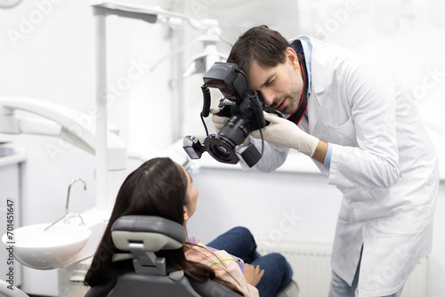 Male dentist taking before and after photo of female patient's teeth in dental office with modern equipment. Dentistry and dental care