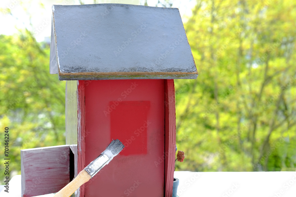 preparing a birdhouse for the new spring season, painting the house white with a paint brush, large strokes on the surface, the concept of a bird's housewarming, helping animals preparing a birdhouse for the new spring season, painting the house white with a paint brush, large strokes on the surface, the concept of a bird's housewarming, helping animals