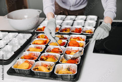 Foto Caterer in a professional kitchen preparing individual servings of roasted vegetables, showcasing meticulous food service