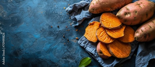 Sweet potato Cut sweet potato over blue table Sweet potato sliced ready to prepare baked pie with vegetables Top view. Creative Banner. Copyspace image photo