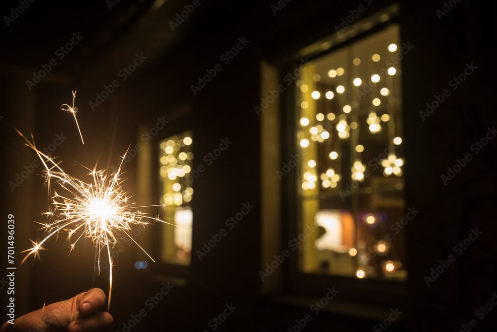 zimny ogień na tle okien domu przybranych ozdobami bożonarodzeniowymi. - obrazy, fototapety, plakaty 