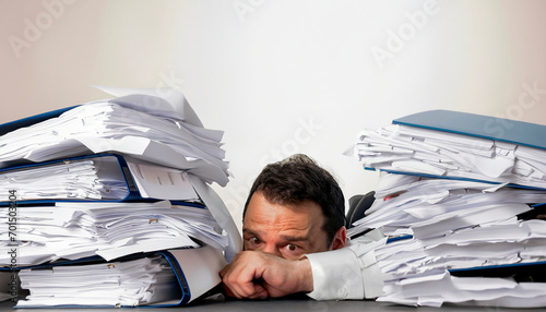 Man with tie, buried in papers at his work table in the office. Work overload concept. Stress. Lifestyle. photo