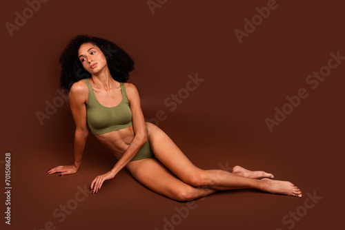 Photo of gorgeous lovely lady no retouch sporty athletic body sitting floor advertising activewear isolated on brown color background