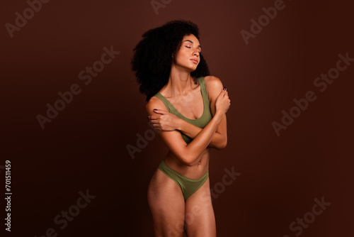 No filter studio photo of tempting shiny woman wear lingerie embracing herself empty space isolated brown color background