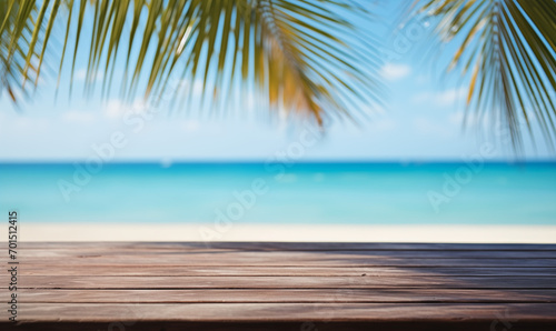 A wooden table on an exotic beach, palm leaves on a blurry background, with the blue ocean in the background. Holiday atmosphere
