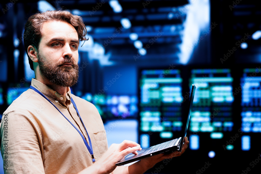 Fototapeta premium Expert IT programmer using laptop to assess supercomputer cybersecurity dangers arising due to unsecured network connections. Supervisor ensuring high tech facility is impenetrable by malware attacks