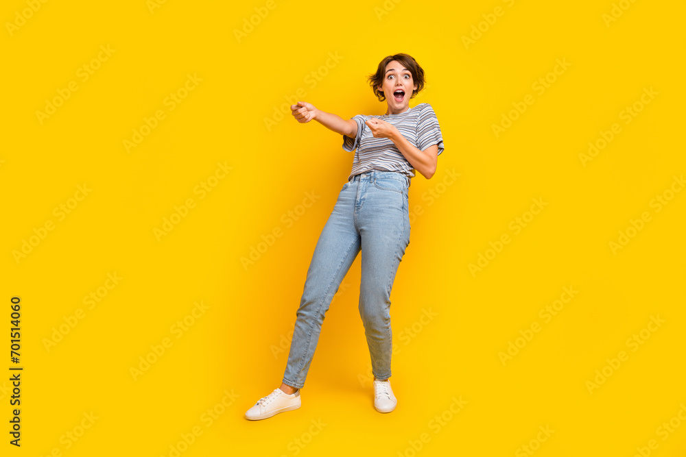 Fototapeta premium Full size portrait of astonished girl arms pull empty space rope string isolated on yellow color background