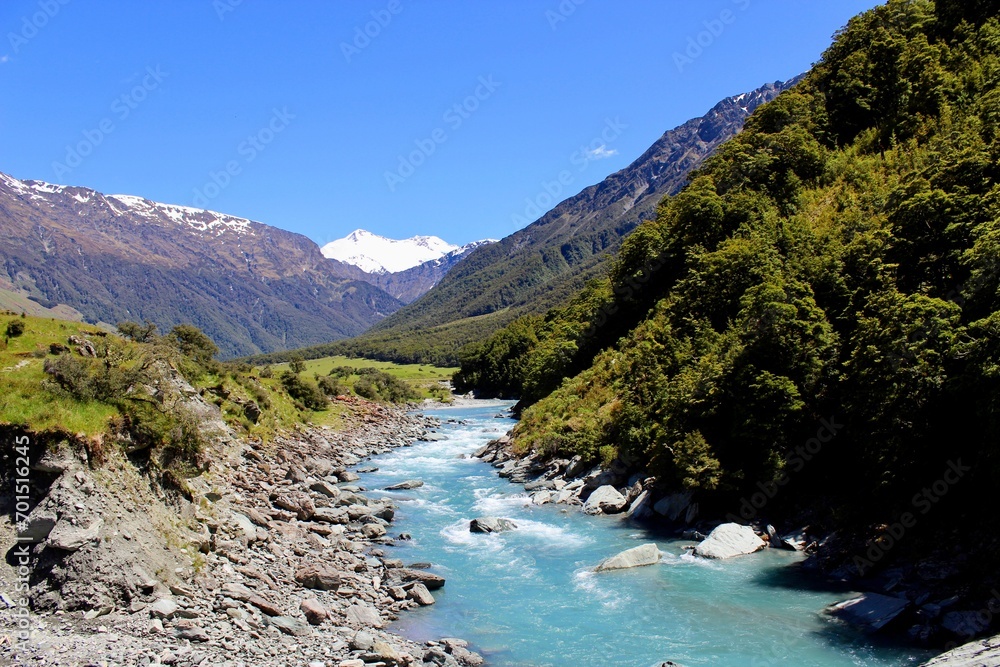 New zealand river blue water with green rocks and mountains with snow