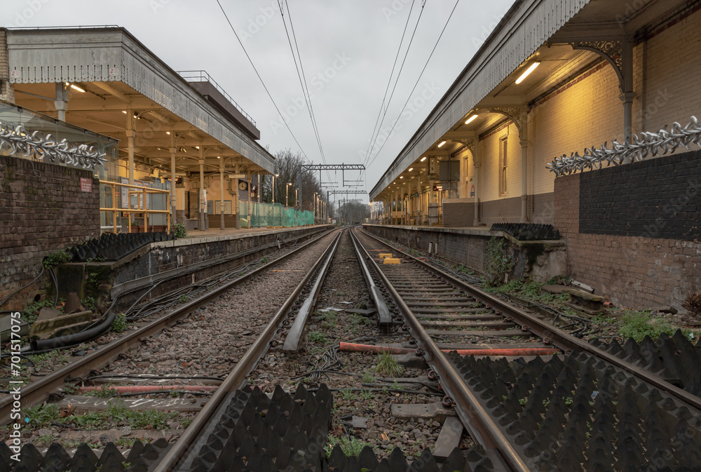 Perspective view on empty railway tracks and electric infrastructure equipment, wires at Acton central rail station. The Railway system with Metal frames of Train platform, Transport and shipping land