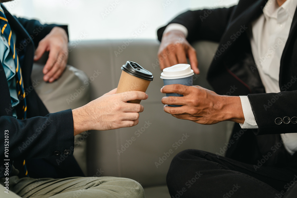 Two men in professional attire on sofa, discussing business matters such as investments or legal topics.