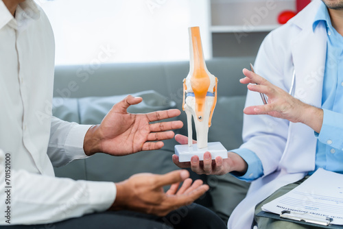 Konstfotografi male patient and male doctor discussing a model of a knee joint, likely focusing on condition of knee arthritis during a medical consultation