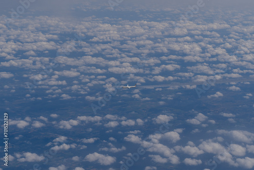 The plane flies in the sky with clouds. Overall plan.