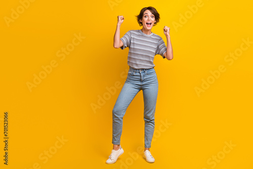 Full length photo of lovely cheerful girl champion football fan celebrate victory empty space isolated on yellow color background © deagreez