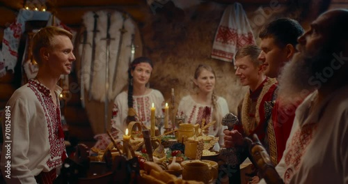 ancient Slavic ritual dinner, man and woman sitting at table in old wooden house, 4K, Prores