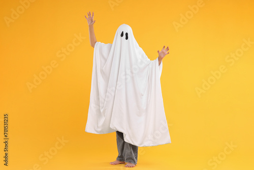 Woman in white ghost costume on yellow background. Halloween celebration