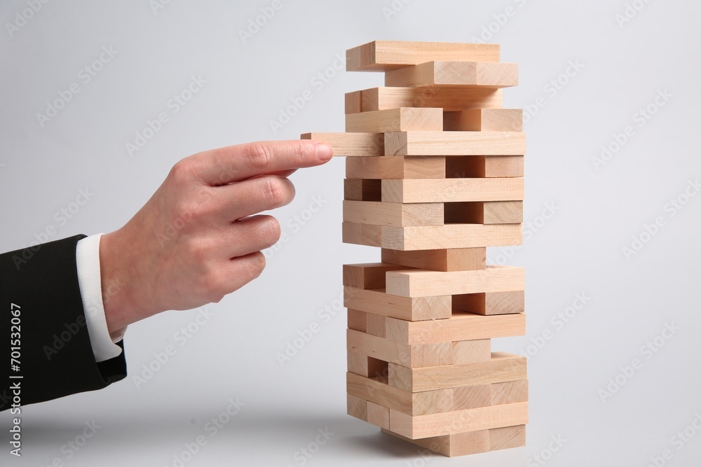Woman playing Jenga on light gray background, closeup Woman playing Jenga on light gray background, closeup