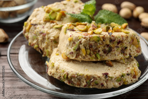 Tasty halva with pistachios and mint on wooden table, closeup photo