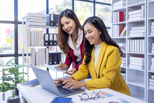 Successful asian business people giving each other a high five in a meeting. Two young business professionals celebrating teamwork in an office.