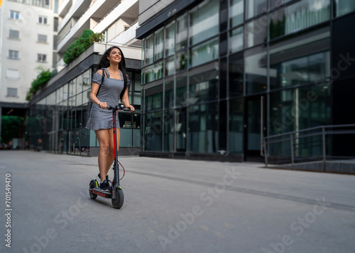 Young European long hair girl, enjoy riding her e scooter through the city, full speed ahead 