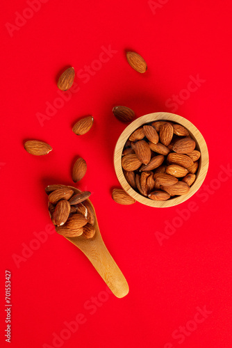 Seed almonds in wooden cup and spoon wooden on red background © apinya