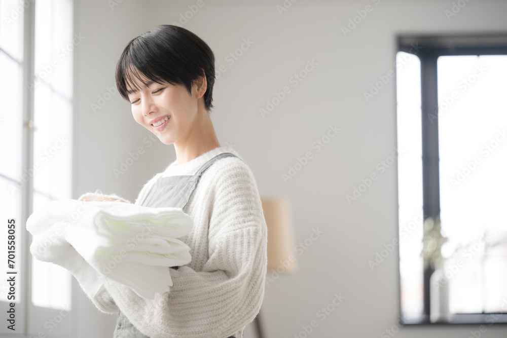 窓際で洗濯物を持つ女性 窓際で洗濯物を持つ女性