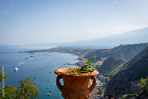 Decorative clay Amphora pot with succulent plants with Taormina aerial view in the background