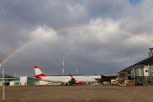 Beautiful rainbow over Basel Euroairport. Plane parked at the gate photo