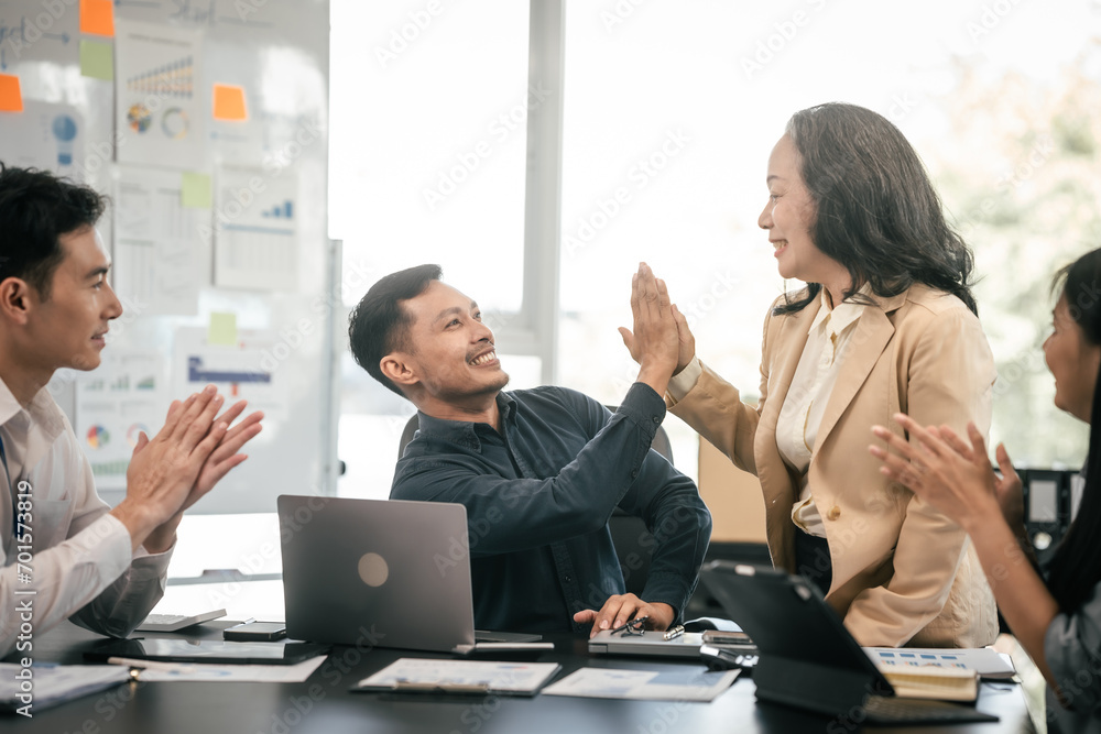 diverse group of Asian professionals, including middle-aged and mature individuals, gathered around a table in a business setting, discussing documents with focused attention.